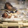 Nurse tending to infant in incubator. 