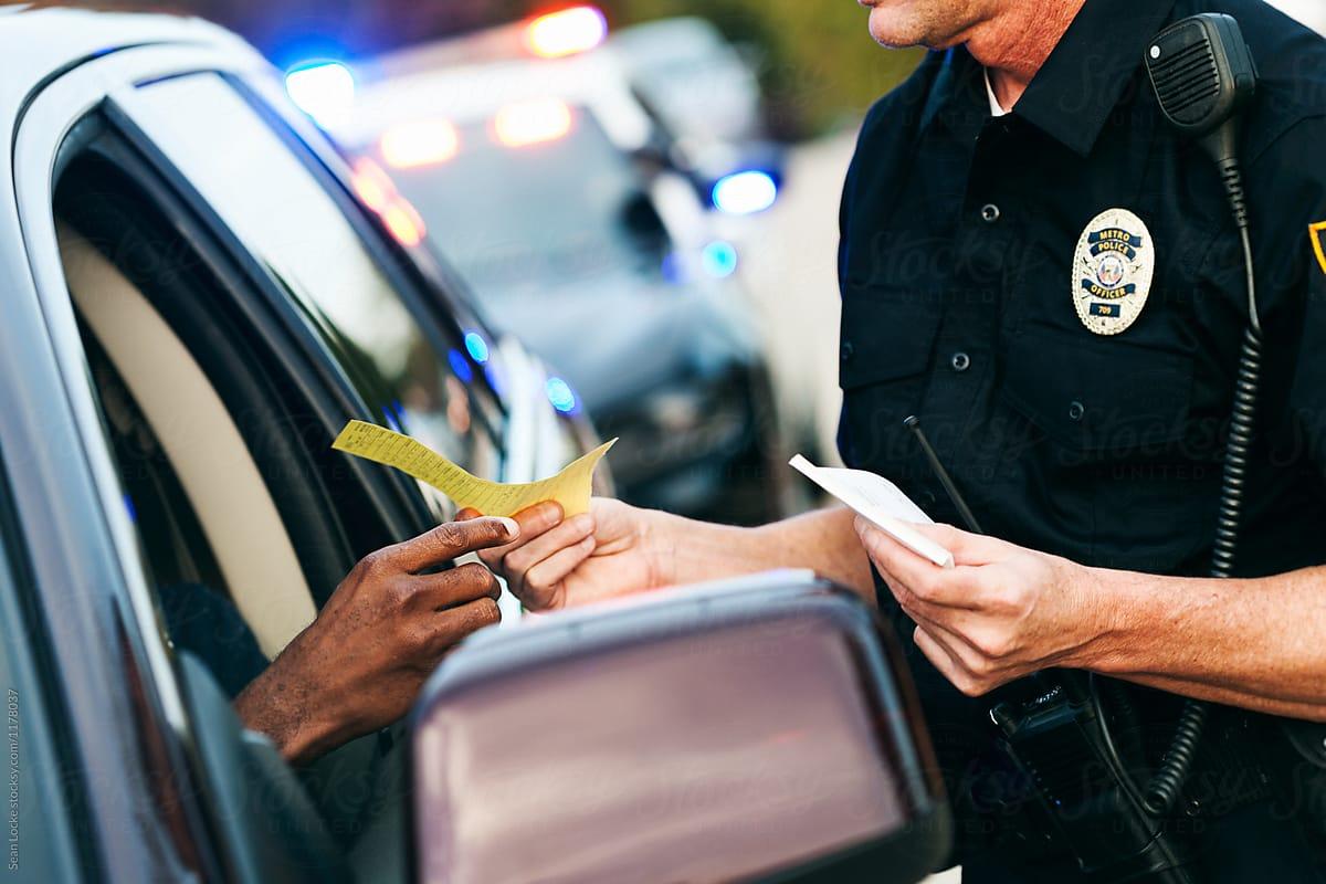 A police officer handing a driver a ticket