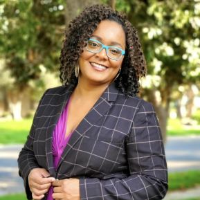 Image of female with blue glasses wearing a black blazer.