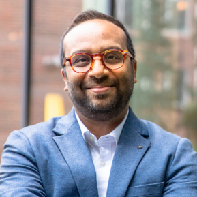 Image of male wearing a blue suit and brown glasses