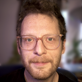 Image of male wearing brown glasses and a black t-shirt