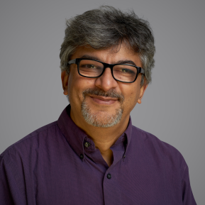 Image of male with grey hair wearing a purple shirt.