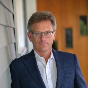 image of male with glasses, wearing a blue suit and white shirt