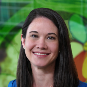 image of female wearing a blue top with brown hair, standing in front of a green graphic background