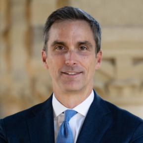 image of male wearing a blue suit, white shirt and blue tie