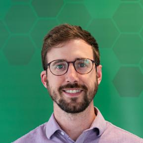 Image of male with a beard, wearing glasses and a pink shirt