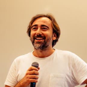 image of male with brown hair wearing a white shirt holding a mic