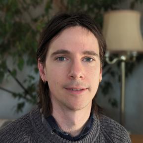 image of male with brown hair wearing a grey sweater