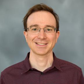 image of male wearing glasses with brown hair and a maroon shirt