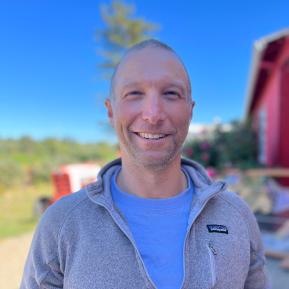 image of male wearing a grey sweater and blue shirt