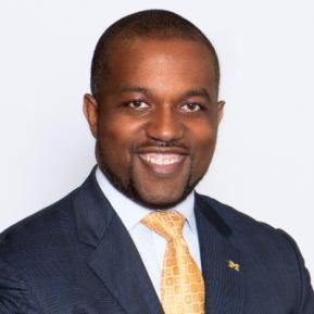 image of male wearing a black suit with yellow tie