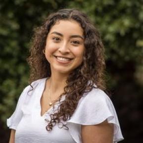 image of female with curly brown hair wearing a white top