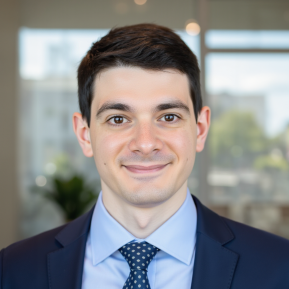 Image of male with black hair wearing a blue suit and blue shirt