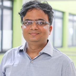 Image of male with glasses wearing a grey shirt