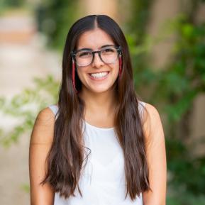 image of female with brown hair wearing glasses and a white top