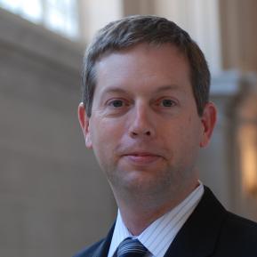 person with brown hair wearing a black suit