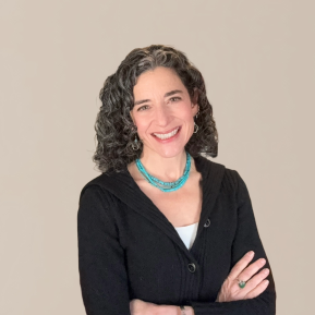 image of woman with curly grey hair wearing a black sweater and blue necklace