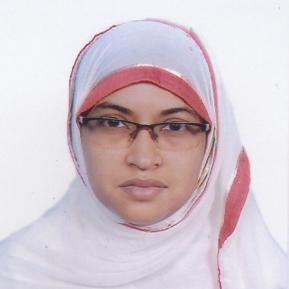 A woman wearing a white hijab with red trim and glasses is looking directly at the camera. She has a serious expression and is dressed in a modest, light-colored outfit. The background is plain white, highlighting her face and attire.