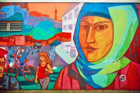 A colorful mural depicting a street scene, featuring a woman in a headscarf