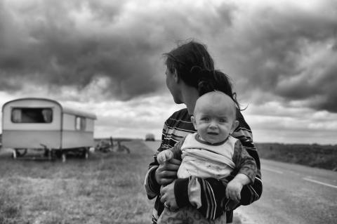 Black-and-white image of a woman holding a baby in a rural area