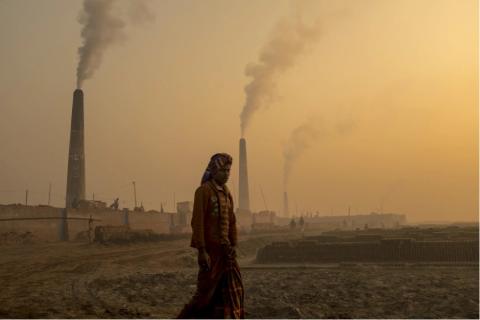 A man in front of smokestacks with high levels of air pollution