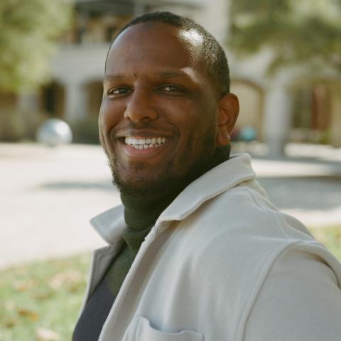 male wearing a green top and white jacket
