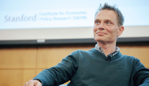 man wearing a green sweater sitting and looking away from the camera