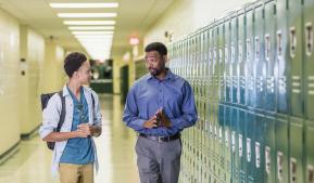 Teacher and student talking in a school hallway