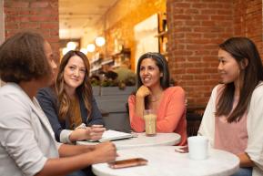 Four women talking around tables