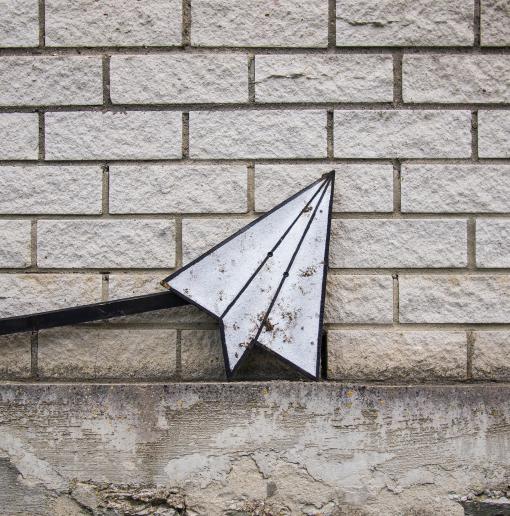 brick wall with paper airplane against it