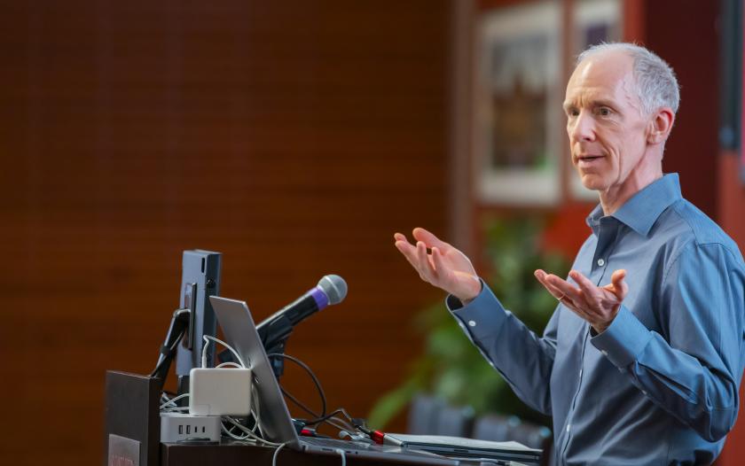 man wearing a blue shirt standing in front of a podium